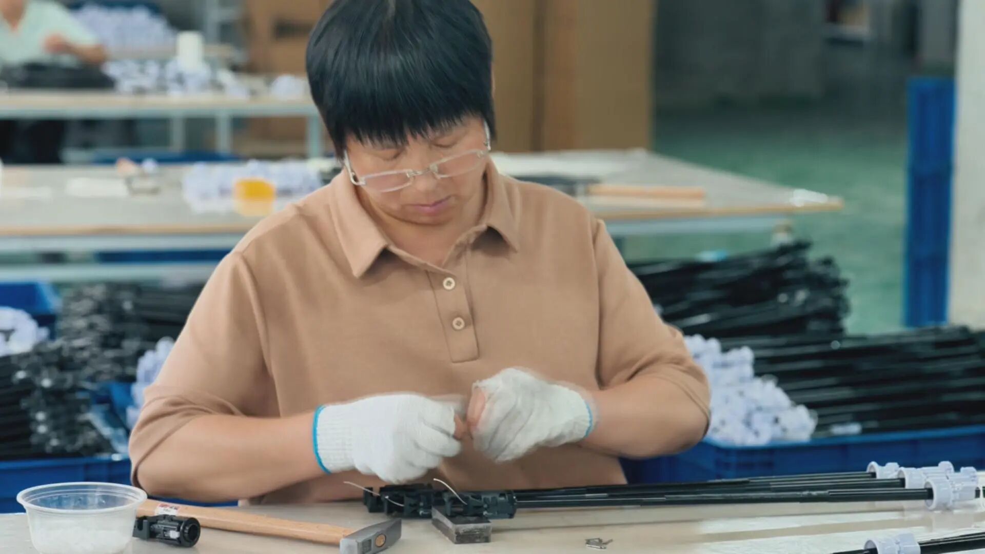 工厂员工在工作台前仔细组装伞架。.jpg